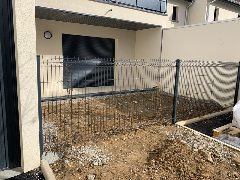 Clôture grillagée rigide de couleur anthracite fermant un jardin.