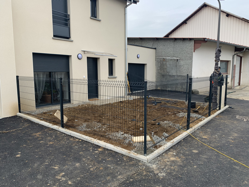 Clôture grillagée rigide de couleur anthracite fermant un jardin.