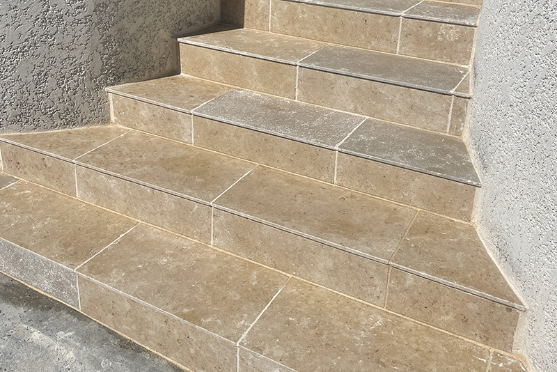 Escalier carrelé donnant accès à une maison.