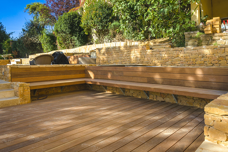 Terrasse en bois réalisée par un paysagiste, munie d'un banc.